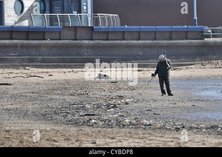 Uomo sabbia spazzatrice con il rivelatore di metalli e portante forcella sul Lytham St Annes beach Foto Stock