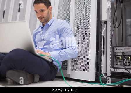L'uomo concentrandosi su computer portatile collegato al server Foto Stock