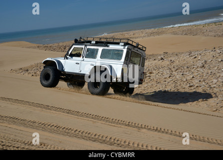 Off road expedition preparato 2012 Land Rover Defender 110 con pneumatici a palloncino, verricello roll cage, luci spot su sabbia in Marocco Foto Stock