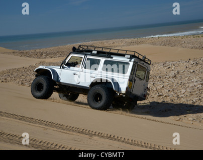 Off road expedition preparato 2012 Land Rover Defender 110 con pneumatici a palloncino, verricello roll cage, luci spot su sabbia in Marocco Foto Stock