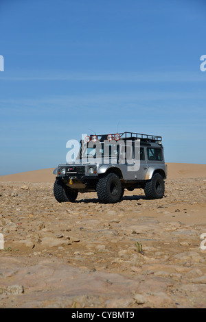 Off road expedition preparato 2012 Land Rover Defender 110 con pneumatici a palloncino, verricello roll cage, luci spot su sabbia in Marocco Foto Stock