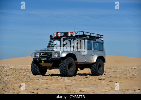 Off road expedition preparato 2012 Land Rover Defender 110 con pneumatici a palloncino, verricello roll cage, luci spot su sabbia in Marocco Foto Stock