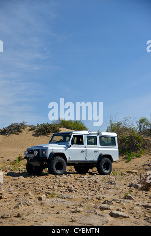 Off road expedition preparato 2012 Land Rover Defender 110 con pneumatici a palloncino, verricello roll cage, luci spot su sabbia in Marocco Foto Stock