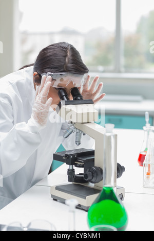 Donna che guarda attraverso il microscopio Foto Stock