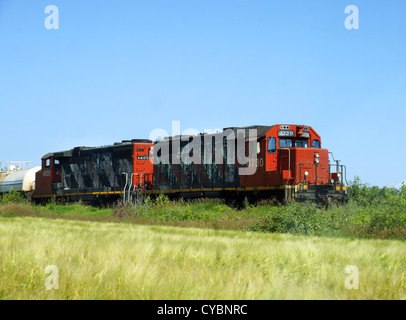 Due vecchi o di trasporto di locomotive cargo attraversa terreni agricoli o praterie di consegnare prodotti e mercanzie. Foto Stock