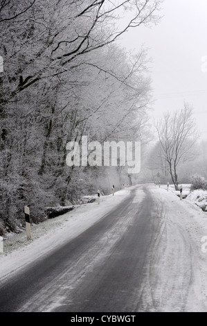 Strada ghiacciata in corrispondenza del bordo di una foresta coperta con trasformata per forte gradiente frost Foto Stock