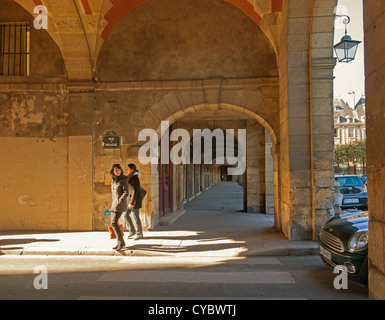 Rue de Birague e gallerie di Place des Vosges. Due donne a piedi sotto il re del padiglione portico della storica piazza. Foto Stock