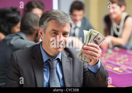 Uomo con il denaro al tavolo della roulette Foto Stock
