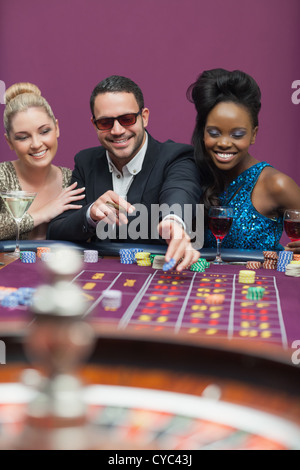 Uomo che indossa gli occhiali da sole con le donne alla roulette Foto Stock