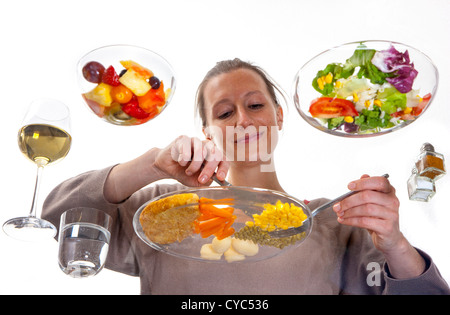 Giovane donna è seduta al tavolo di vetro. Mangiare un pasto, Schnitzel, patate, verdure, insalata mista, insalata di frutta, vino bianco. Foto Stock