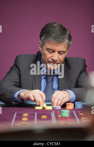 L'uomo afferrando i chip e il gioco della roulette Foto Stock