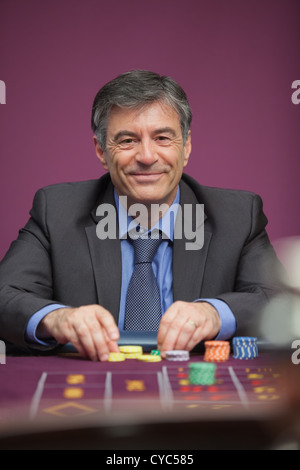 Uomo sorridente giocare alla roulette in un casinò Foto Stock
