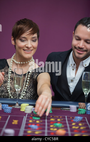 Donna immissione puntata alla roulette con uomo Foto Stock