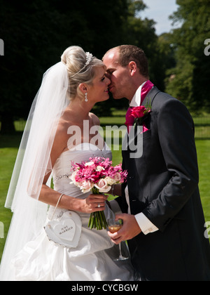 La sposa e lo sposo condividono un affettuoso bacio sulla loro giorno di nozze Foto Stock