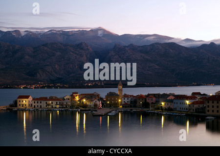 Piccola città costiera di Vinjerac in Croazia al mattino presto con mare calmo, riflessi in acqua e montagne sullo sfondo. Foto Stock