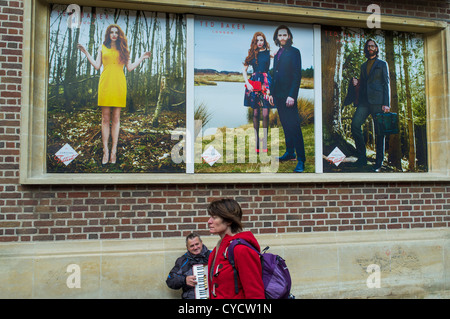 Il 31 ottobre 2012. Exeter Devon England. Un suonatore ambulante di fisarmonica su un umido autunno il giorno sotto Ted Baker pubblicità. Foto Stock