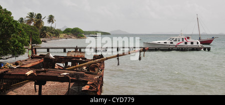 Blue Sky costa, guardando a Nord, di ferro arrugginito naufragio di poppa freighter, imbarcazione attraccata jetty, sopravvento, Carriacou, West Indies Foto Stock