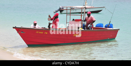 L uomo lo sterzo, uomo in piedi la pesatura pesce, uomo in piedi sul mare rosso guida barca da pesca su Paradise Beach, Carriacou, West Indies Foto Stock