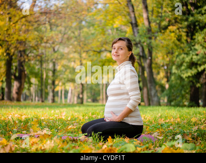 Giovane donna incinta rilassante all'aperto nella bella la natura in autunno Foto Stock