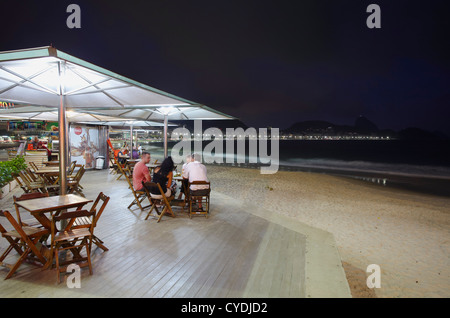 Le persone al bar sulla spiaggia al tramonto, Copacabana, Rio de Janeiro, Brasile Foto Stock