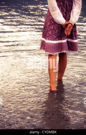 Una ragazza in un abito vintage è in piedi in acqua Foto Stock