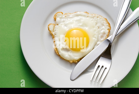 Uovo fritto su una piastra con posate Foto Stock