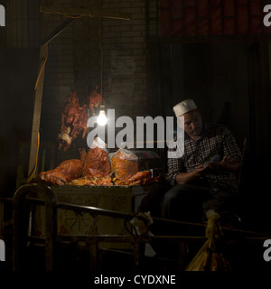 Uyghur uomo nel suo Foodstall nel mercato notturno, Hotan, Xinjiang Uyghur Regione autonoma, Cina Foto Stock