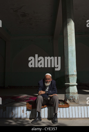 Il vecchio uomo uigura in appoggio al di fuori della moschea, Yarkand, Xinjiang Uyghur Regione autonoma, Cina Foto Stock