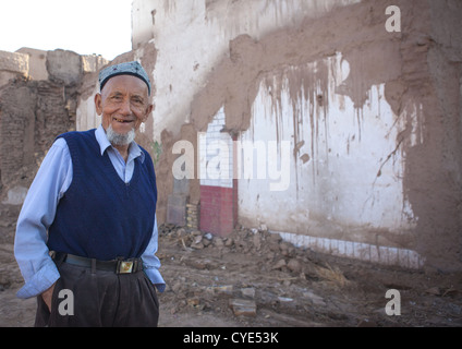 Uyghur uomo nella parte anteriore della demolita Casa, Città Vecchia di Kashgar, Xinjiang Uyghur Regione autonoma, Cina Foto Stock
