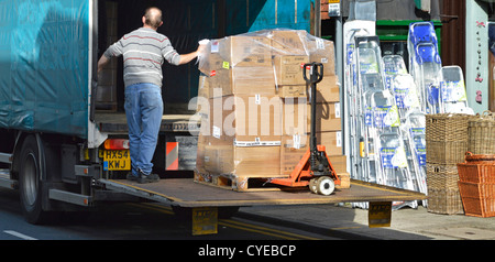 High Street negozio riceve la merce presso il fornitore consegna delle scatole impilate su pallet carrello abbassato sulla pedana sollevatrice da camionista Sevenoaks Regno Unito Foto Stock