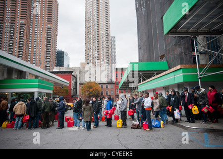 Linea di persone fino ad acquistare benzina a un Hess stazione di gas nel quartiere di Clinton di Manhattan a New York Foto Stock