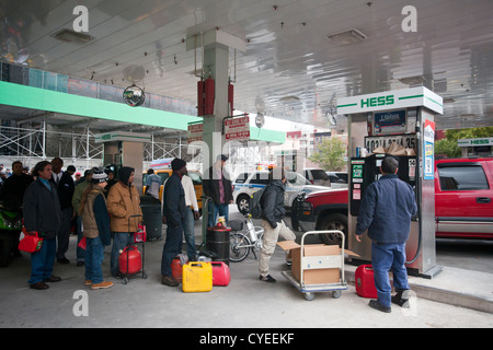 Linea di persone fino ad acquistare benzina a un Hess stazione di gas nel quartiere di Clinton di Manhattan a New York Foto Stock