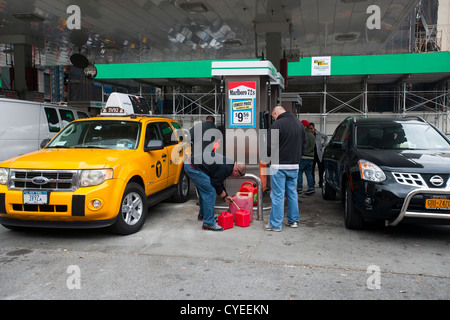 Linea di persone fino ad acquistare benzina a un Hess stazione di gas nel quartiere di Clinton di Manhattan a New York Foto Stock