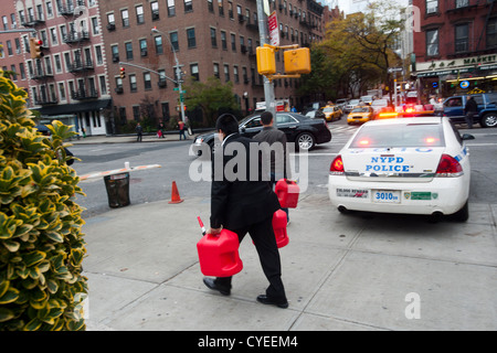 Linea di persone fino ad acquistare benzina a un Hess stazione di gas nel quartiere di Clinton di Manhattan a New York Foto Stock