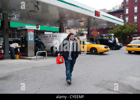 Linea di persone fino ad acquistare benzina a un Hess stazione di gas nel quartiere di Clinton di Manhattan a New York Foto Stock