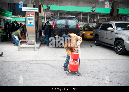 Linea di persone fino ad acquistare benzina a un Hess stazione di gas nel quartiere di Clinton di Manhattan a New York Foto Stock