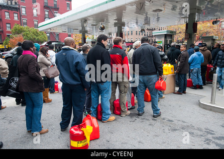 Linea di persone fino ad acquistare benzina a un Hess stazione di gas nel quartiere di Clinton di Manhattan a New York Foto Stock