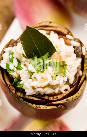 Carciofi Ripieni con risotto sul tavolo elegante con forca d'oro Foto Stock