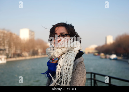 Parigi, Francia - una giovane donna che indossa cappotto e sciarpa in inverno una giornata di sole, di fronte al Canal Foto Stock