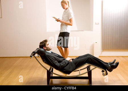 Lettura donna uomo disteso sulla chaise longue Foto Stock