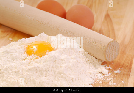 Uova sfuse su tagliere in legno con farina e rotella per ravioli Stock  Photo