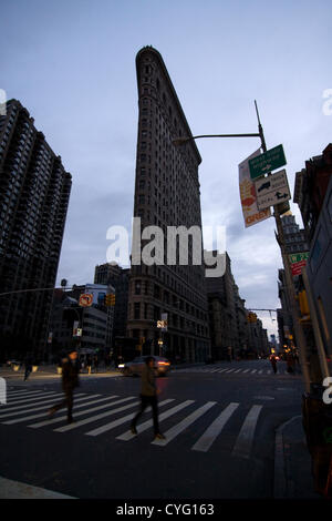 New York STATI UNITI D'AMERICA. Il 1 novembre 2012. Guardando a Sud sulla Quinta Avenue e 23rd Street nel quartiere di Chelsea di New York City. L'iconico Flatiron Building con assenza di luci in Windows come i newyorkesi scurry in crosswalk sul quinto viale illuminato solo dai fari di un veicolo. Lampioni e semafori rimangono al buio quattro giorni dopo l uragano sabbiosa potenza di taglio per parti della città al di sotto di 29th Street. Foto Stock