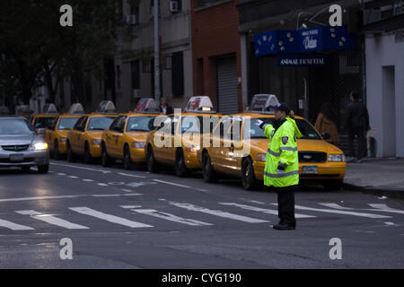 New York STATI UNITI D'AMERICA. Il 1 novembre 2012. NYPD funzionario di polizia indossando giacca riflettente dirige il traffico sulla 21st Street e la 7th Avenue nel quartiere di Chelsea di New York City. Parti della città è scura a causa di una mancanza di alimentazione a Manhattan sotto 29th St dagli effetti della sabbia di uragano che ha colpito la zona di lunedì ottobre 29th. Foto Stock