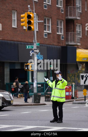 New York STATI UNITI D'AMERICA. Il 1 novembre 2012. NYPD funzionario di polizia indossando giacca riflettente dirige il traffico su 23rd Street e la 7th Avenue in New York City. I semafori sono scuri a causa di una mancanza di alimentazione a Manhattan sotto 29th St a causa degli effetti della sabbia di uragano che ha colpito la zona di lunedì ottobre 29th. Foto Stock