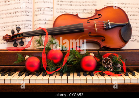 Un violino si siede su un pianoforte circondato da decorazioni per le feste Foto Stock