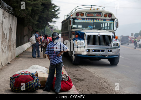 Un ragazzo attende il bus tradizionale in Antigua, Guatemala. Foto Stock