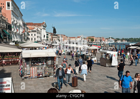 Turisti e bancarelle di souvenir sulla Riva degli Schiavoni, Venezia lungomare vicino a Piazza San Marco Foto Stock