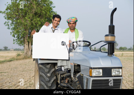 Advisor finanziario mostrando un cartello con un agricoltore su un trattore Foto Stock