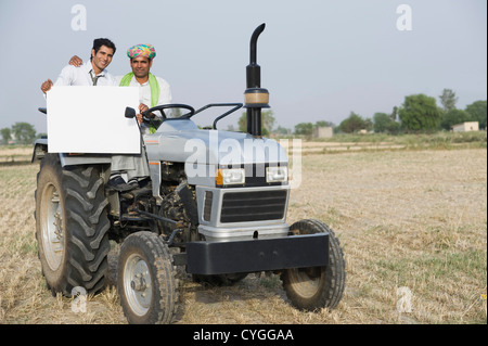 Advisor finanziario mostrando un cartello con un agricoltore su un trattore Foto Stock