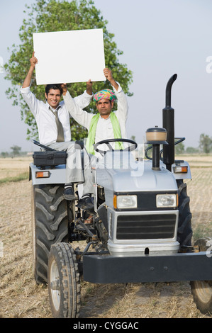 Advisor finanziario e da un contadino che mostra una targhetta su un trattore Foto Stock